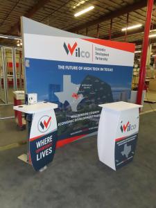 SYK-1014 Symphony Portable Display w/ SEG Fabric Graphic, (2) Backwall Workstations, Wireless Charging Pads, Monitor Mount, LED Stem Lights, and an SYM-408 Reception Counter with Locking Storage